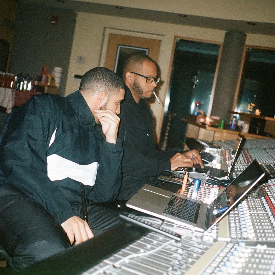 Drake and a producer using a console as a laptop stand.